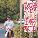 A cyclist rides past a homemade sign on the way to Ironsâ€™ memorial (AP photo)