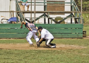 An Outlaw baserunner eludes the tag and touches home plate.