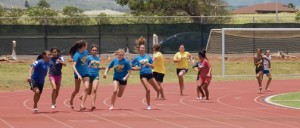Chaos is averted as competitors successfully pass batons after the first leg of the girlsâ€™ sixth and seventh grade 440-yard relay.